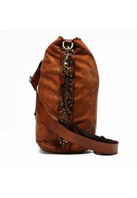 Borsa in pelle marrone dalla forma arrotondata, con borchie e dettagli in metallo lungo il lato, e una tracolla in pelle removibile.