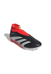 Zapato de fútbol negro con una parte superior tipo calcetín roja, que presenta franjas diagonales plateadas y una suela blanca con acentos rojos, diseñado para un agarre óptimo.