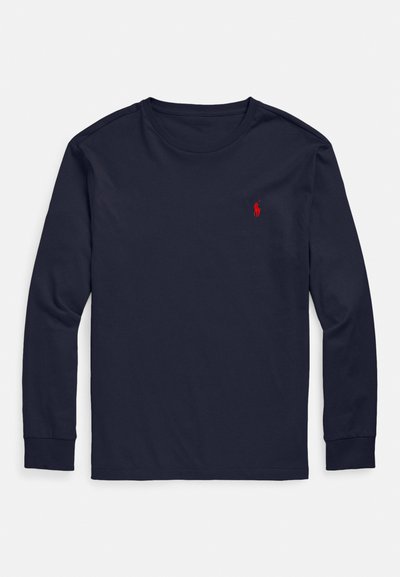 Tengerészkék hosszú ujjú pamutpóló; kerek nyakkivágással és egy kis piros hímzett logóval a bal mellrészen. Sima tapintású.