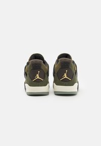 Zelené a černé semišové tenisky s bílou podrážkou, zdobené zlatým logem na patě a texturovanými detaily na zadní straně.