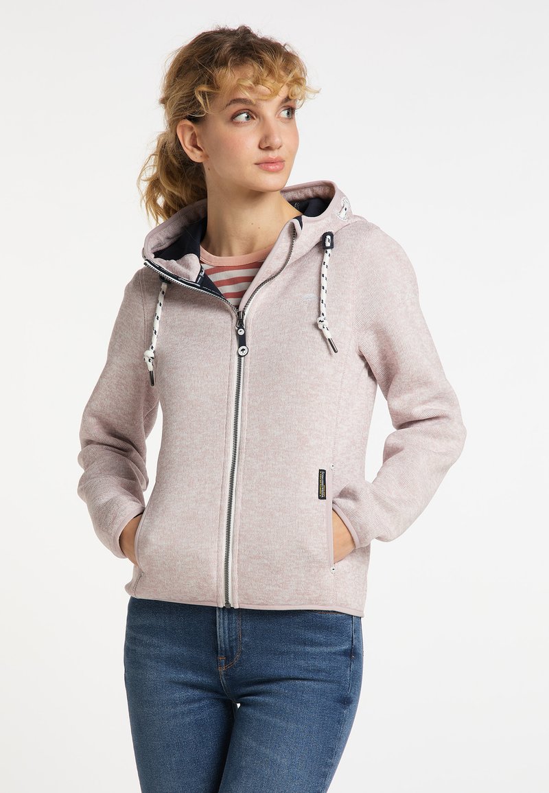Hoodie rosa chiaro con zip, realizzato in tessuto morbido, dotato di cappuccio, chiusura con zip anteriore e dettagli con coulisse; abbinato a jeans blu.