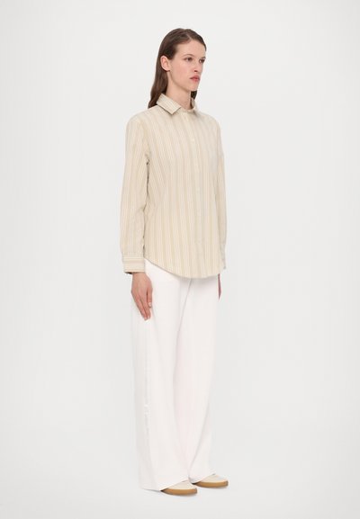 Beige striped button-up shirt with long sleeves, paired with white wide-leg pants and beige slip-on shoes. Smooth fabric texture, casual fit.