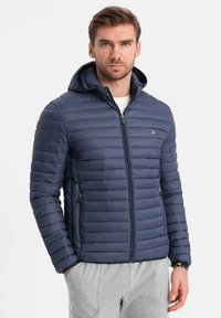 Giacca puffer blu navy con cappuccio, caratterizzata da cuciture orizzontali e due tasche laterali con zip. Realizzata in un tessuto leggero e isolante.