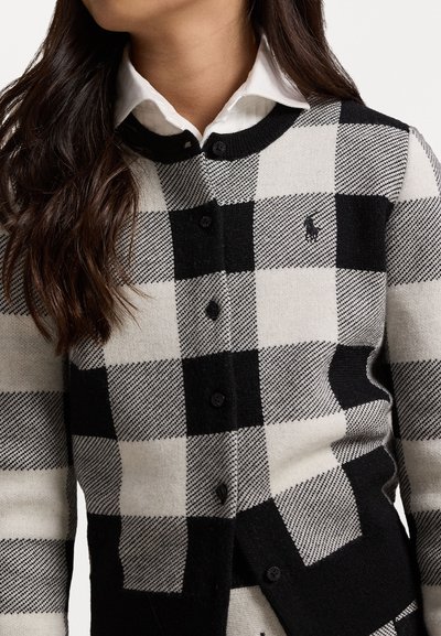 Cardigan a scacchi bianco e nero realizzato in morbido materiale lavorato a maglia, con collo rotondo, chiusura con bottoni e un piccolo logo distintivo.
