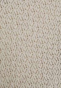 Tissu tricoté couleur crème avec un motif en dentelle détaillé de formes losanges et une texture ajourée.