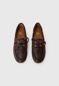 Brune loafers med vevet tekstur, semskede detaljer, snøring og gullige maljer. Designet har en avrundet tå og polstret såle.