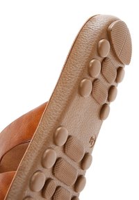 Semelle de chaussure en cuir marron avec des grips en caoutchouc ronds et texturés disposés en rangées pour la traction et la durabilité.