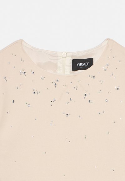 Beige fabric with scattered small silver sequins, round neckline, and visible Versace brand label sewn inside.