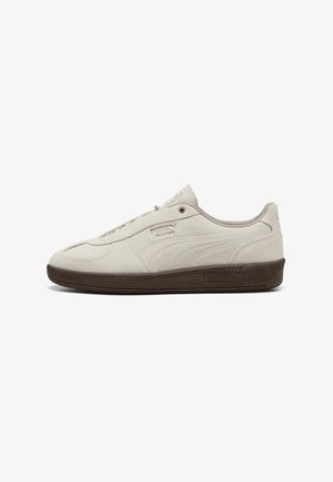 Jasnobeżowy sneaker Puma Palermo z cholewką z zamszu oraz ciemnobrązową gumową podeszwą, pokazany z profilu na białym tle.
