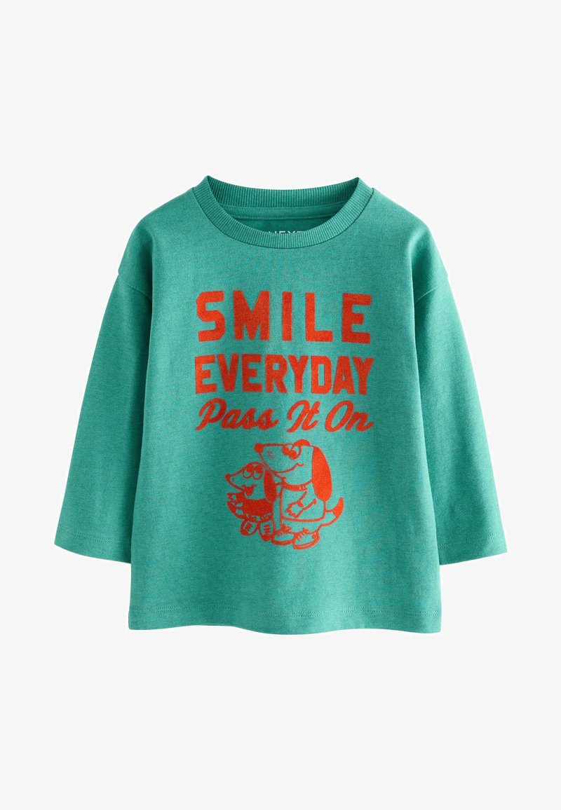 Green long-sleeve shirt with red text "SMILE EVERYDAY Pass It On" and two cartoon dogs wearing sunglasses below the text.