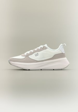 Biały i jasnoszary casualowy sneaker z grubą podeszwą, wiązany na sznurówki, z logo po boku oraz pętelką na pięcie na neutralnym tle.