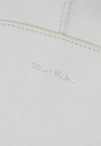 Superficie in pelle bianca con testo impresso "GERRY WEBER" e una sottile texture in rilievo, caratterizzata da un design minimalista.