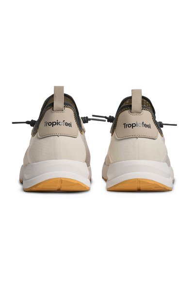 Paire de baskets Tropicfeel beige et blanches avec semelles en caoutchouc orange, vue de dos, avec languettes de tirage et lacets noirs ajustables.