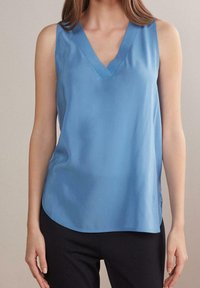 Blå ärmlös topp i mjukt tyg, med V-ringning och rundad nederkant, i en avslappnad passform och sidovisningar för extra komfort.