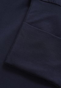 Mörk marinblått tyg med en slät textur, med en vikt del som visar både sömmen och en synlig fickdesign.