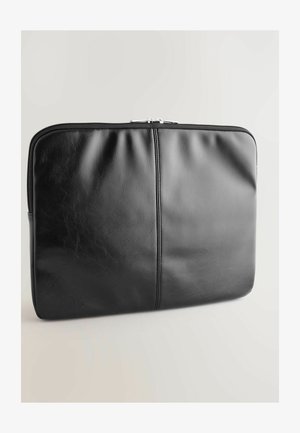 Husa pentru laptop din piele neagră, cu o textură netedă, detalii cu cusături duble și un sistem de închidere cu fermoar sigur. Formă rectangulară cu margini rotunjite.