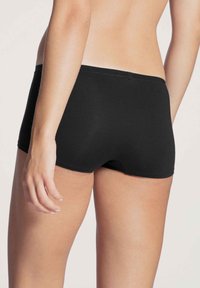 Zwarte katoen boyshorts met een gladde textuur, voorzien van een middelhoge tailleband en een strakke pasvorm, ontworpen voor comfort en bewegingsgemak.
