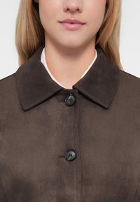 Brown suede coat featuring a wide collar, black buttons, and a smooth texture, with a clean, straightforward design.