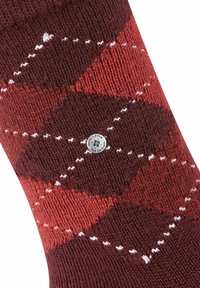 Calzino a rombi rosso e marrone, realizzato in tessuto lavorato a maglia, con cuciture diagonali bianche e una piccola etichetta con logo argento.