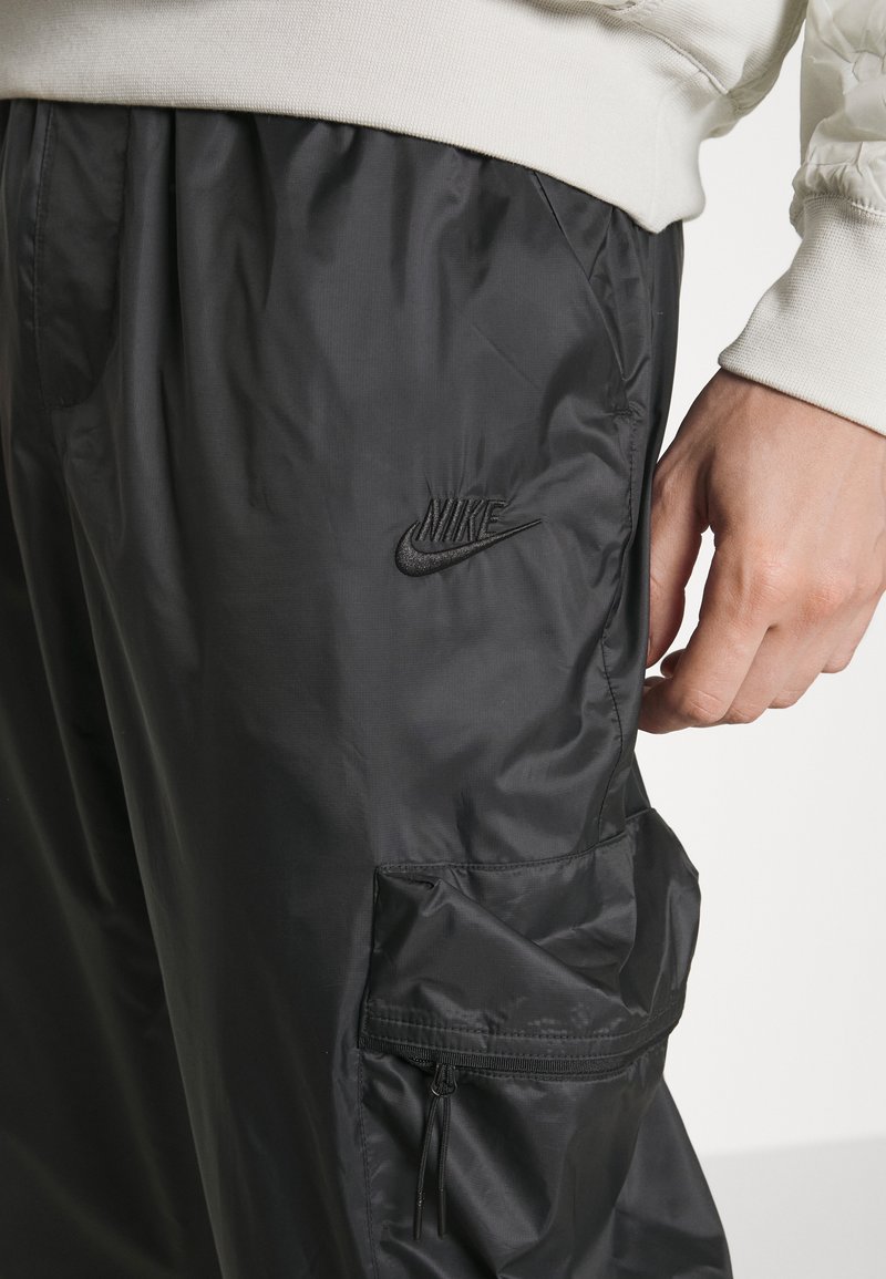 Schwarze Nylon-Jogger mit einer Seitentasche, elastischem Bund und gesticktem Nike-Logo auf dem linken Oberschenkel.