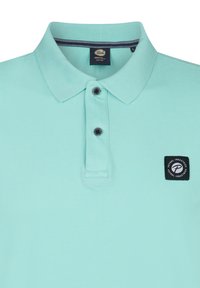 Ljusblå piké skjorta i bomull med ribbat krage, två mörka knappar och en fyrkantig logotyp patch på vänster bröst.