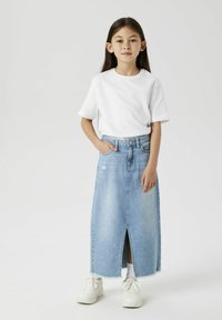 Maxi-Jeansrock mit Schlitz vorne, getragen über einem weißen Rundhals-T-Shirt. Das Outfit wird mit weißen Sneakers kombiniert.