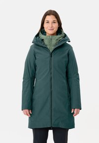 Parka impermeabile di colore verde scuro con zip frontale, cappuccio regolabile e strato interno trapuntato di colore verde chiaro. Texture liscia e maniche lunghe.