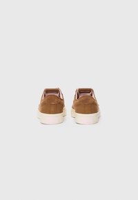 Brown corduroy sneakers with a low profile, pink accents on the heel, and a textured surface. White rubber sole visible at the base.