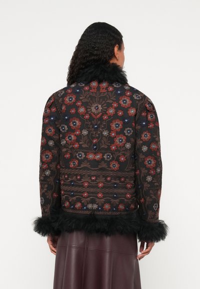 Jakna s cvetličnim vzorcem iz temnega blaga z rdečimi, modrimi in sivimi detajli. Ima črn umetni krzneni ovratnik in obrobne detajle.