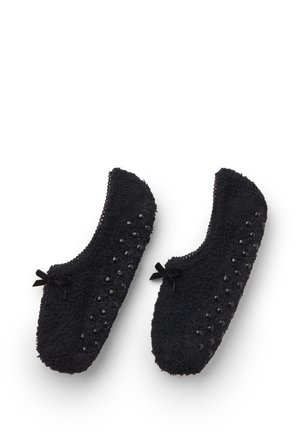 Paar schwarze, flauschige Hausschuhe mit rutschfesten Gummipunkten an den Sohlen und kleinen dekorativen Schleifen oben.