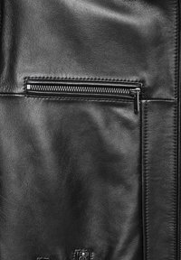 Zwarte leren jas met een ritszak, zachte textuur en een klassiek ontwerp met zichtbare stiksels en hardware-accenten.