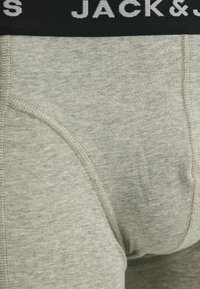 Boxers en coton gris mélangé avec une ceinture élastique noire présentant des lettres blanches. Comprend des coutures plates et un design ajusté.