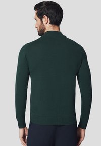 Ciemnozielony dzianinowy sweter o dopasowanym fasonie, okrągłym dekolcie i prążkowanych mankietach. Gładka tekstura i czyste szwy, widok z tyłu.