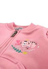 Sweat-shirt à fermeture éclair rose avec un motif de tigre entouré de cœurs et de verdure. Fabriqué en tissu doux, il possède des poignets côtelés et une fermeture éclair lisse.
