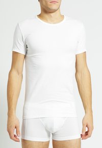 White cotton t-shirt with short sleeves and a round neckline, paired with white form-fitting briefs. Simple design, smooth texture.