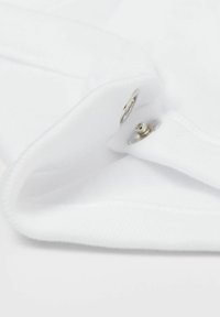 Bílá tkanina s hladkou strukturou má skládaný límec a stříbrné patentky, což zdůrazňuje čisté linie a minimalistický design.