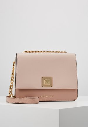 Lichtroze en beige Michael Kors crossbodytas met gouden kettingband en vierkante gouden sluiting op witte ondergrond tegen een grijze achtergrond.