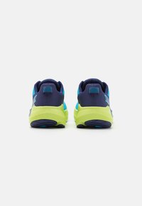 Baskets de sport avec une tige navy, des accents turquoise et une semelle jaune vif. Les caractéristiques comprennent un talon texturé et des détails en mesh à motifs.