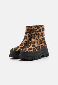 Bottines à imprimé léopard avec une semelle noire épaisse, présentant un design à enfiler et un tissu texturé, idéales pour une meilleure traction.