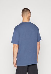 Marineblå bomulds t-shirt med korte ærmer, rund hals og en afslappet pasform. Bagfra ses en glat tekstur og en subtil farvevariation.