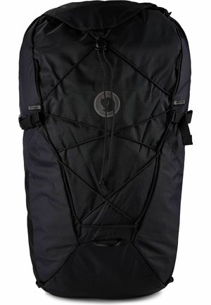 Mochila negra para exteriores con cuerda elástica frontal, correas laterales de compresión y parche redondo con logo en el centro.