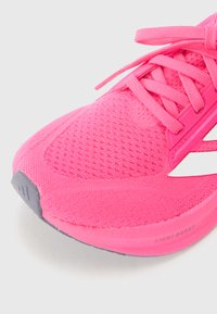 Růžová sportovní bota s prodyšným síťovaným svrškem, plochými tkaničkami a šedou gumovou podrážkou. Na mezipodešvi má značení "LIGHT BOOST".