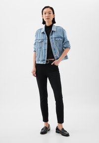 Világoskék farmerdzseki elülső zsebekkel, fekete testhezálló garbó és fekete slim nadrág. Fekete loafer cipővel kiegészítve.