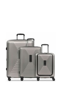 Tre valigie rigide sovrapposte in argento, con un design a coste testurizzate, accentuate da maniglie e ruote nere.