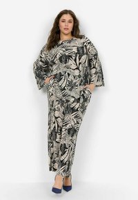 Plus-size playsuit met een zwart-beige bladpatroon, losse pasvorm, lange mouwen met brede manchetten en zijzakken.