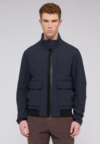 Námornícke bombardovací sako vyrobené z hladkého, elastického materiálu má vysoký límec, přední zip, dvě vakové kapsy a černé žebrované manžety.