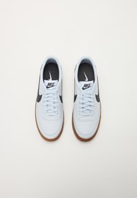 Gaiši zila apavi ar melnu Swoosh logo, balti šņores un gumijas zoli. Iebūvēts gluds ādas augšdaļa un melns iekšējais oderējums.