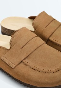Mocassins à enfiler en daim beige avec des détails cousus et des semelles intérieures en liège rembourrées, conçus pour un confort décontracté et une facilité de port.