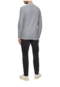 Lichtgrijs, textuurtrui met een kraag, gecombineerd met zwarte broek en witte sneakers. De stof lijkt zacht en casual van stijl te zijn.