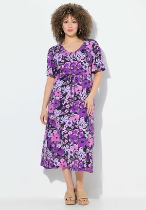Lila blumiges Midi-Kleid mit kurzen Ärmeln und tailliertem Bund; hat pinke und lavendelfarbene Blumen auf einem dunklen Hintergrund. Genossen mit geflochtenen Plateau-Sandalen.